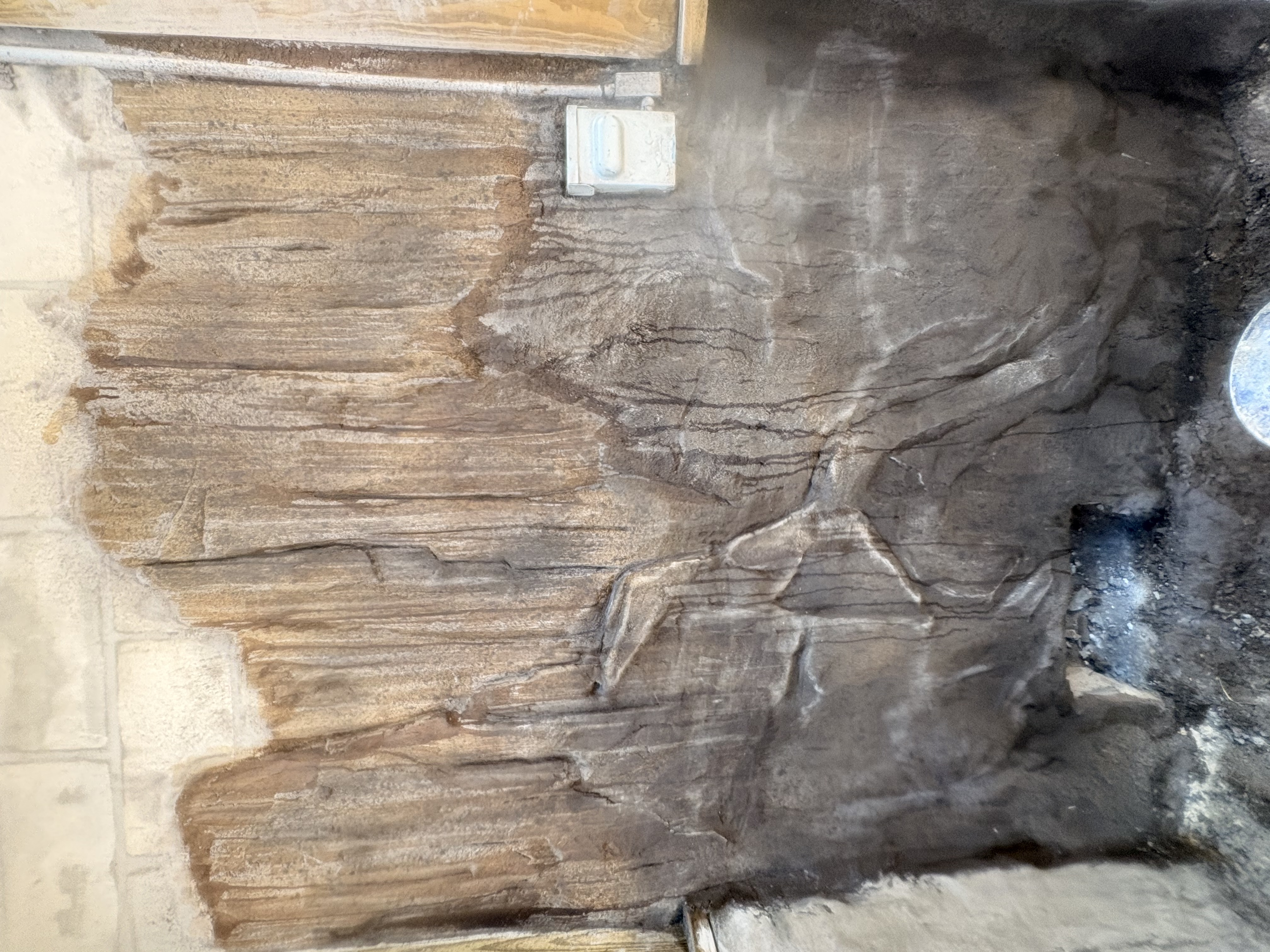 Raw textured wall coat before final detailing, showing the base layer of the sculpted scene